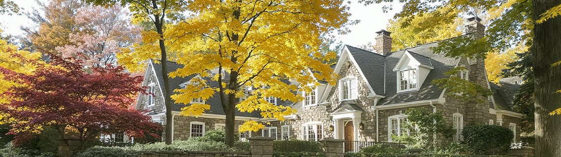 Mature affluent Pennsylvania suburb with large stone-and-shingle homes behind stone walls in autumn