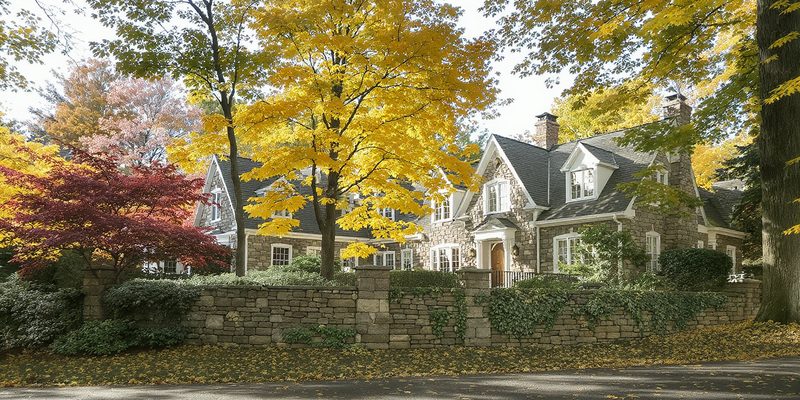 Mature affluent Pennsylvania suburb with large stone-and-shingle homes behind stone walls in autumn