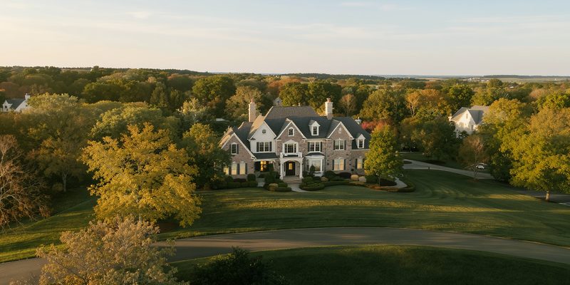 Upscale suburban Pennsylvania street of large brick-and-stone colonial homes with mature oak trees