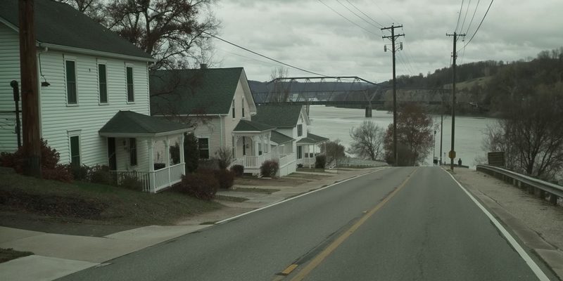 Small Pennsylvania river borough with tidy porched houses sloping toward a steel truss bridge
